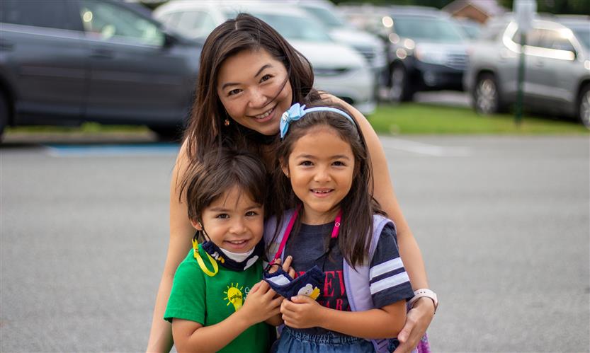 A mother and two students smile